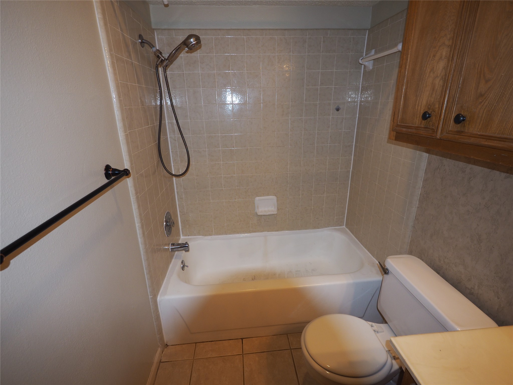 2508 Enfield Road, Unit 10 Austin, TX 78703 - Photo 9 of 17 Bathroom featuring a white bathtub with a tiled shower surround, chrome shower fixtures, a white toilet, and wood-finish cabinetry