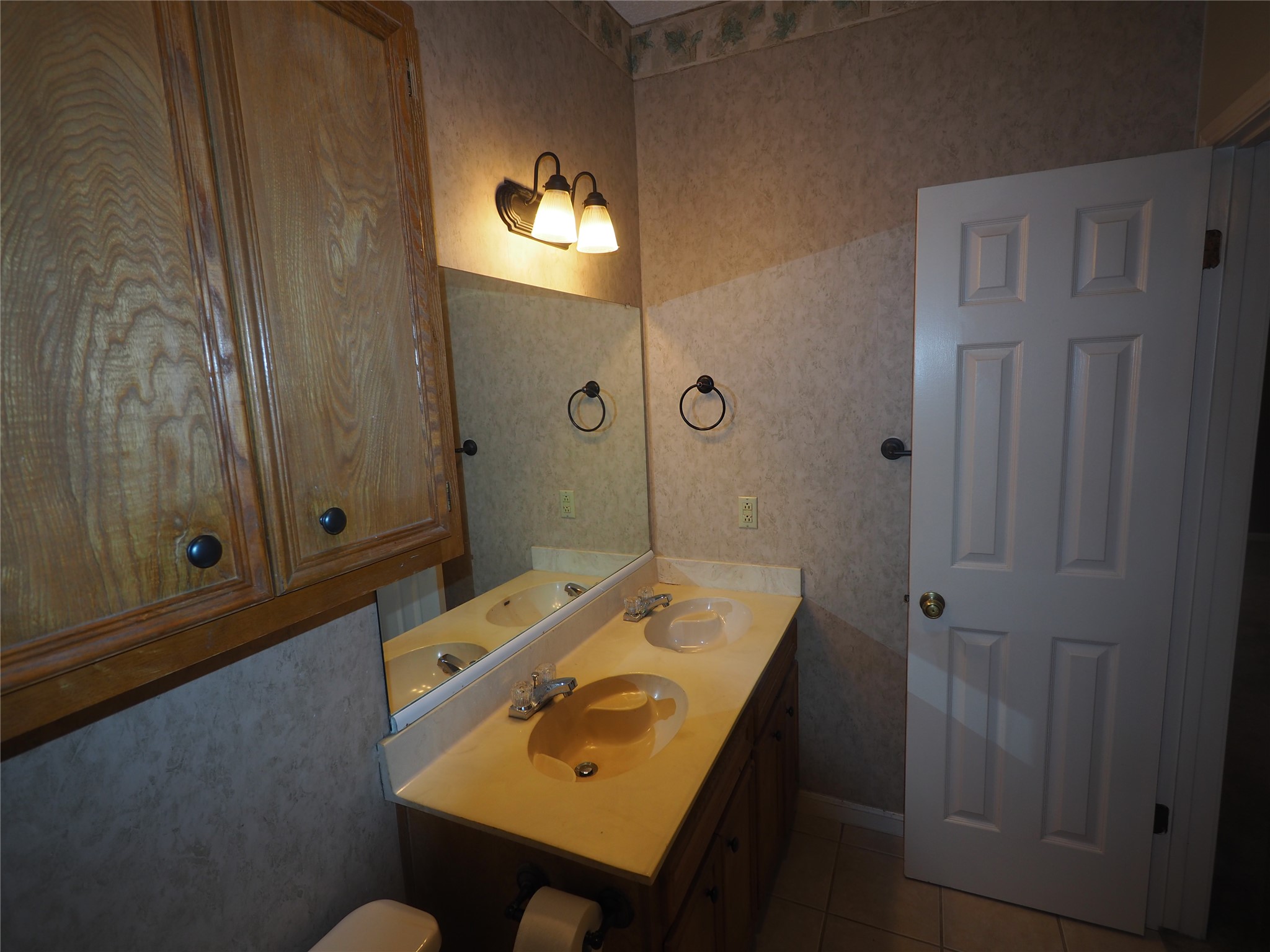 2508 Enfield Road, Unit 10 Austin, TX 78703 - Photo 10 of 17 Dual sink vanity with a light-toned countertop, framed mirror, and warm-toned wall sconce