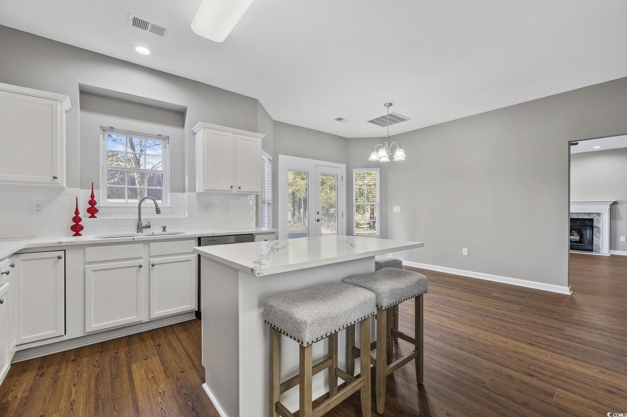 629 Slash Pine Court Myrtle Beach, SC 29579 - Photo 11 of 40 Kitchen with white cabinets, dark wood finished floors, pendant lighting, a breakfast bar, and a kitchen island