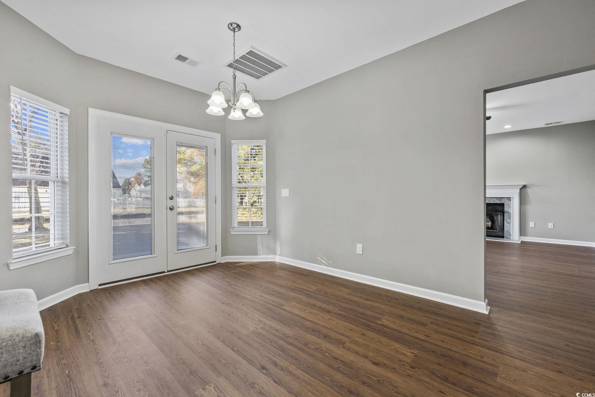 629 Slash Pine Court Myrtle Beach, SC 29579 - Photo 12 of 40 Unfurnished dining area featuring dark wood finished floors, a high end fireplace, a chandelier, and french doors