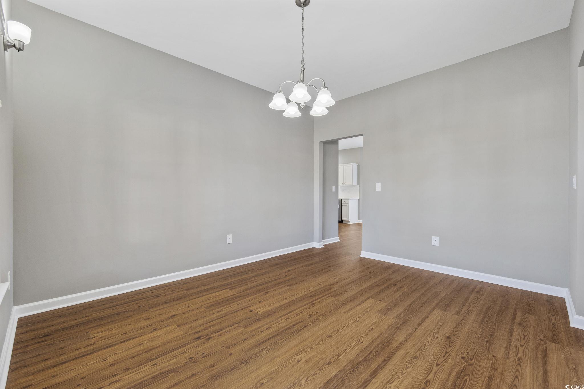 629 Slash Pine Court Myrtle Beach, SC 29579 - Photo 13 of 40 Empty room with dark wood-type flooring and a chandelier