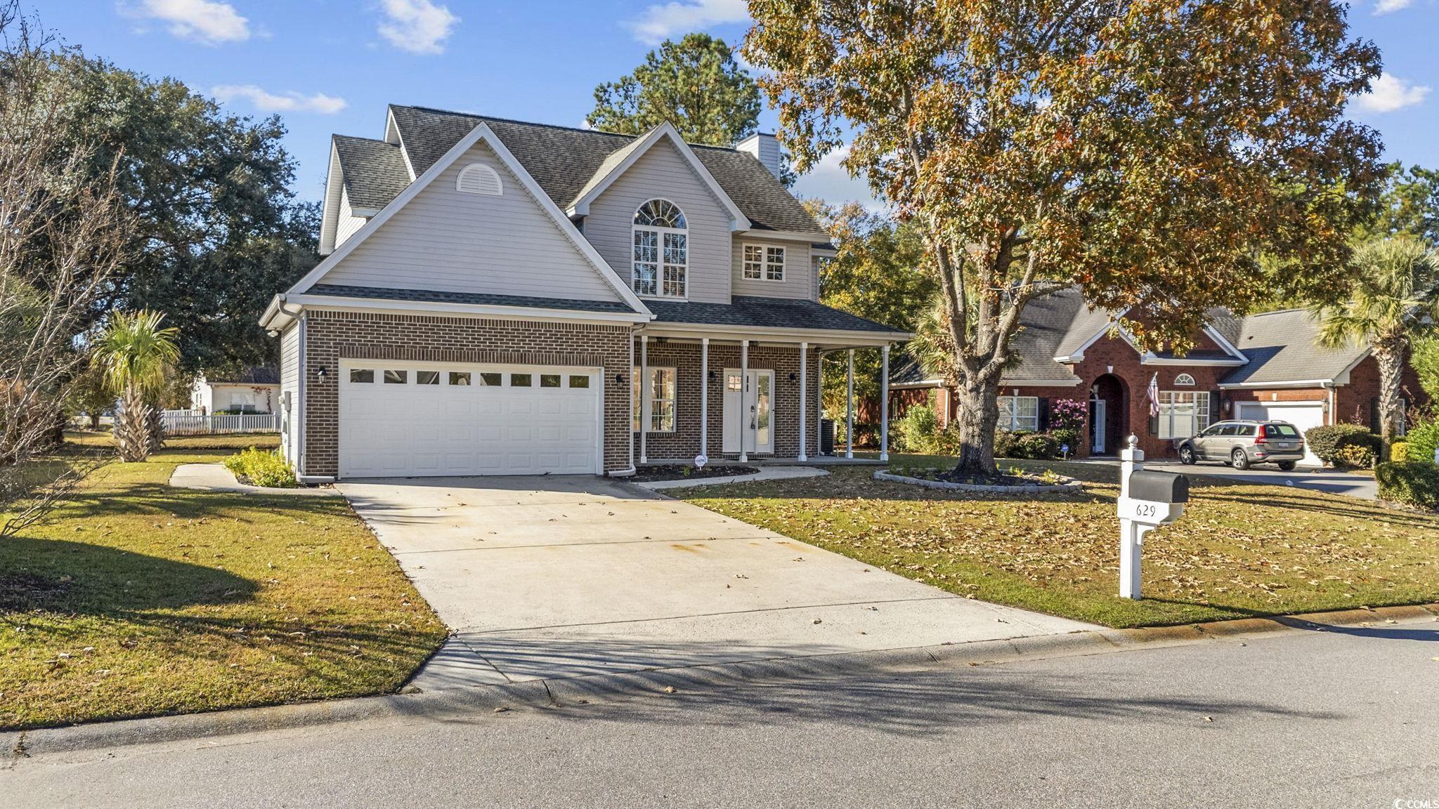 629 Slash Pine Court Myrtle Beach, SC 29579 - Photo 2 of 40 Traditional home featuring a porch, a front yard, concrete driveway, brick siding, and a garage