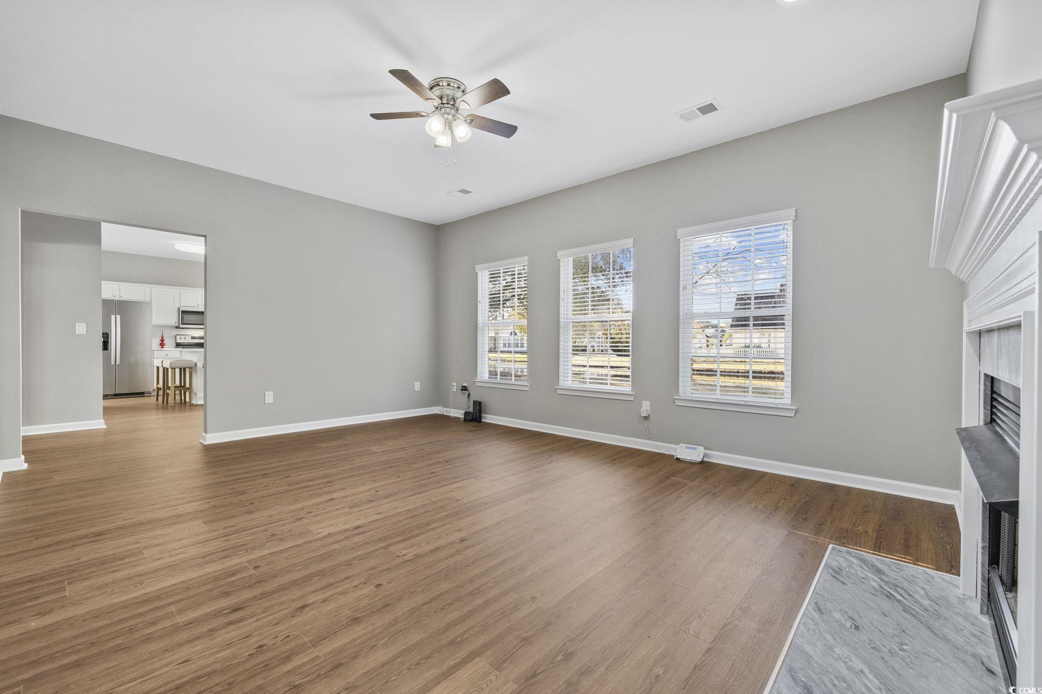 629 Slash Pine Court Myrtle Beach, SC 29579 - Photo 7 of 40 Unfurnished living room featuring dark wood-style floors, a fireplace with flush hearth, and ceiling fan