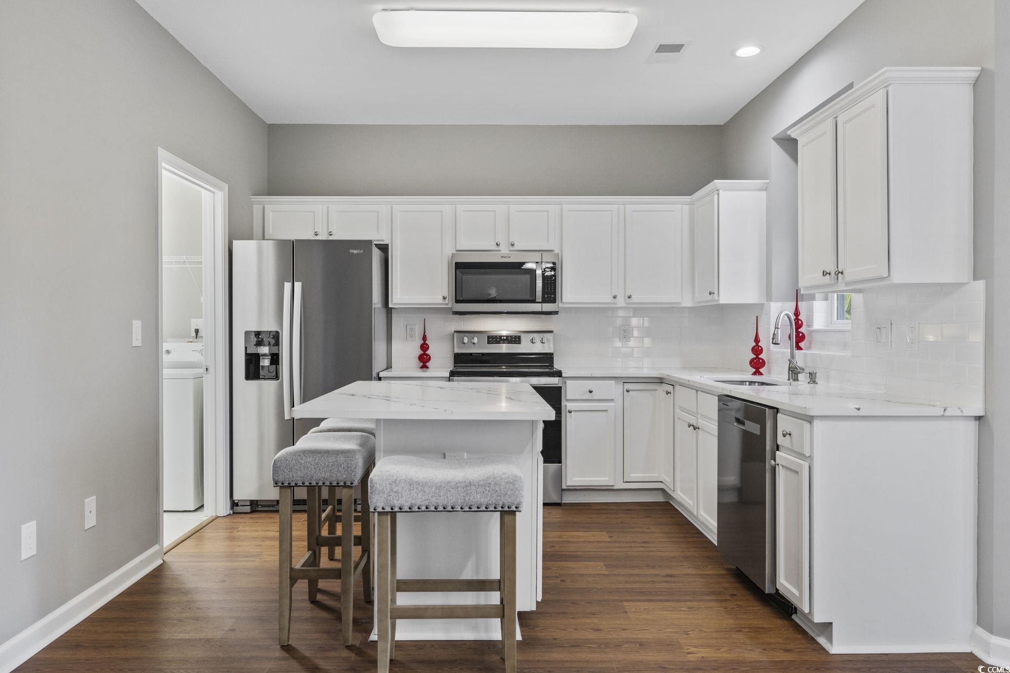 629 Slash Pine Court Myrtle Beach, SC 29579 - Photo 9 of 40 Kitchen with appliances with stainless steel finishes, white cabinets, dark wood finished floors, a kitchen breakfast bar, and recessed lighting