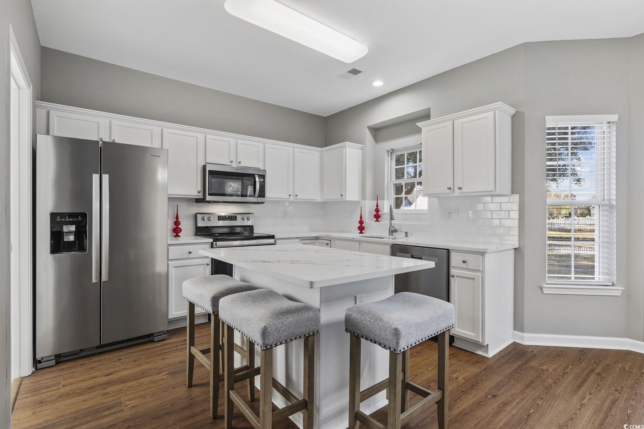 629 Slash Pine Court Myrtle Beach, SC 29579 - Photo 10 of 40 Kitchen featuring stainless steel appliances, white cabinetry, a breakfast bar, dark wood-type flooring, and recessed lighting