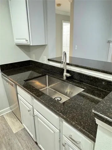 a kitchen with granite countertop white cabinets and a sink