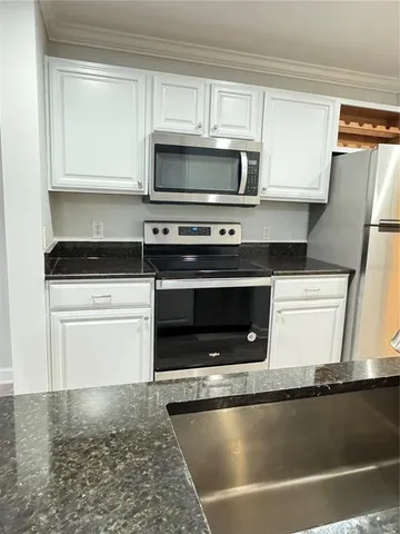 a kitchen with granite countertop a stove microwave and sink