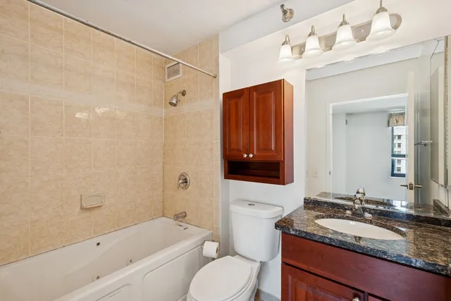 a bathroom with a granite countertop sink a mirror a toilet and bathtub