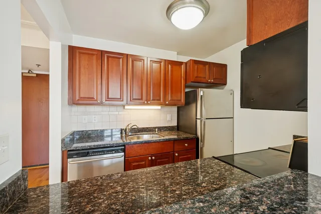 a kitchen with stainless steel appliances granite countertop a refrigerator sink and stove