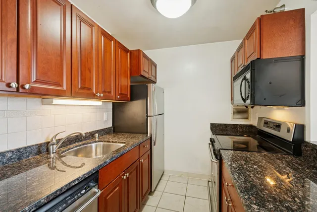 a kitchen with granite countertop a sink a stove and a microwave oven