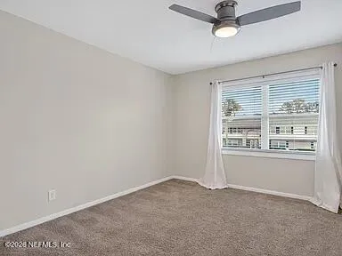 an empty room with a window and ceiling fan