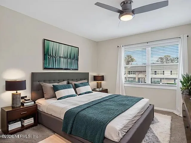 a bedroom with a bed two lamps and a large window