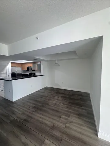 a view of kitchen and empty room with wooden floor
