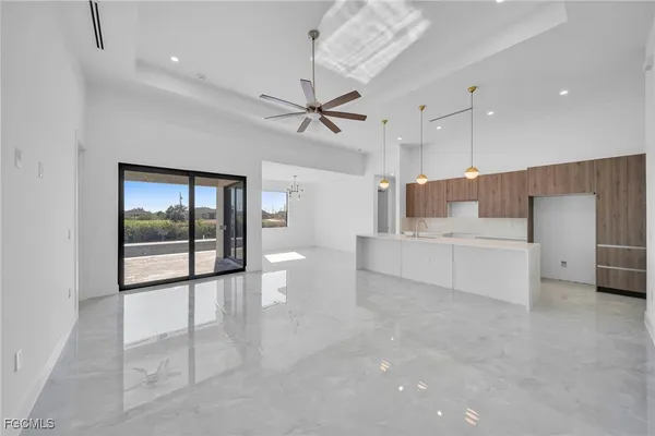 a large white room with kitchen view and a ceiling fan