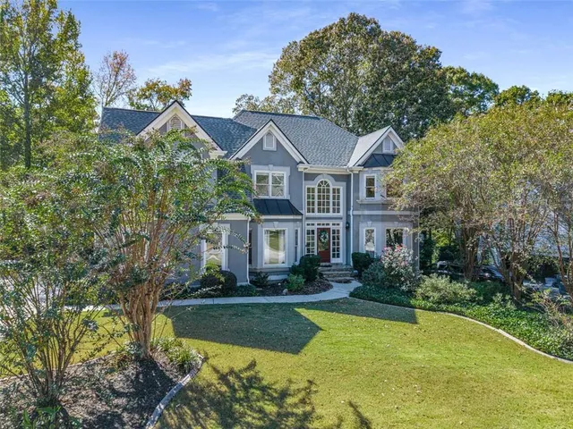 a front view of a house with a yard and large trees