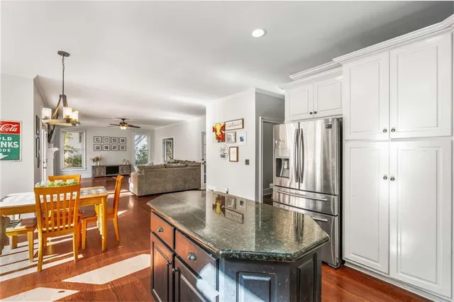 a kitchen with stainless steel appliances granite countertop a refrigerator a sink dishwasher a stove and white cabinets with wooden floor