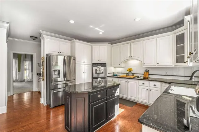 a kitchen with granite countertop a refrigerator stove and wooden floors