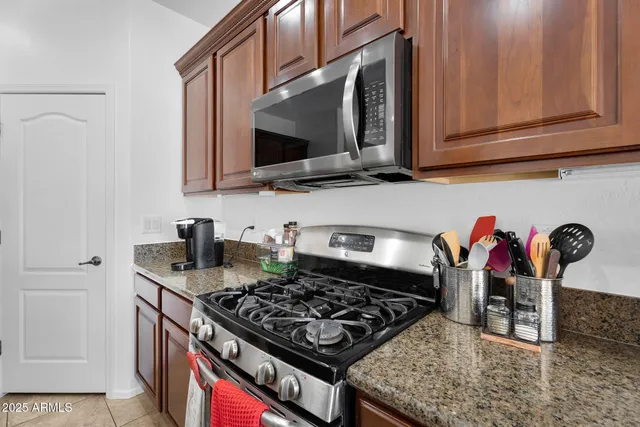 a kitchen with stainless steel appliances granite countertop a refrigerator oven a sink a stove a dining table and chairs