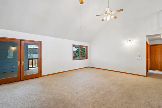 an empty room with chandelier fan and windows