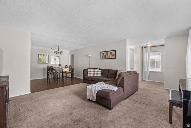 88 East C Street Springville, UT 84663 - Photo 4 of 32 Open-concept living area featuring a spacious carpeted floor, light-toned walls, and a dining area with wood-finish flooring and a multi-bulb chandelier