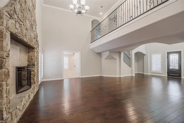 a view of an empty room with wooden floor and a fireplace
