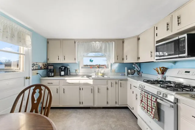 a kitchen with granite countertop white cabinets and white appliances