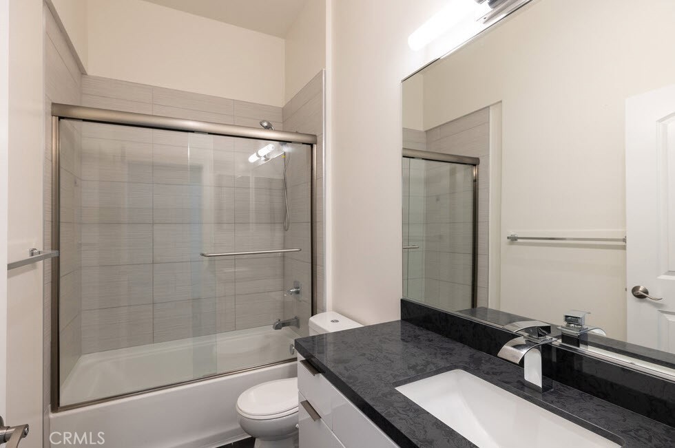 2651 South Hobart Boulevard, Unit 9 Los Angeles, CA 90018 - Photo 5 of 8 a bathroom with a granite countertop sink toilet a mirror and shower