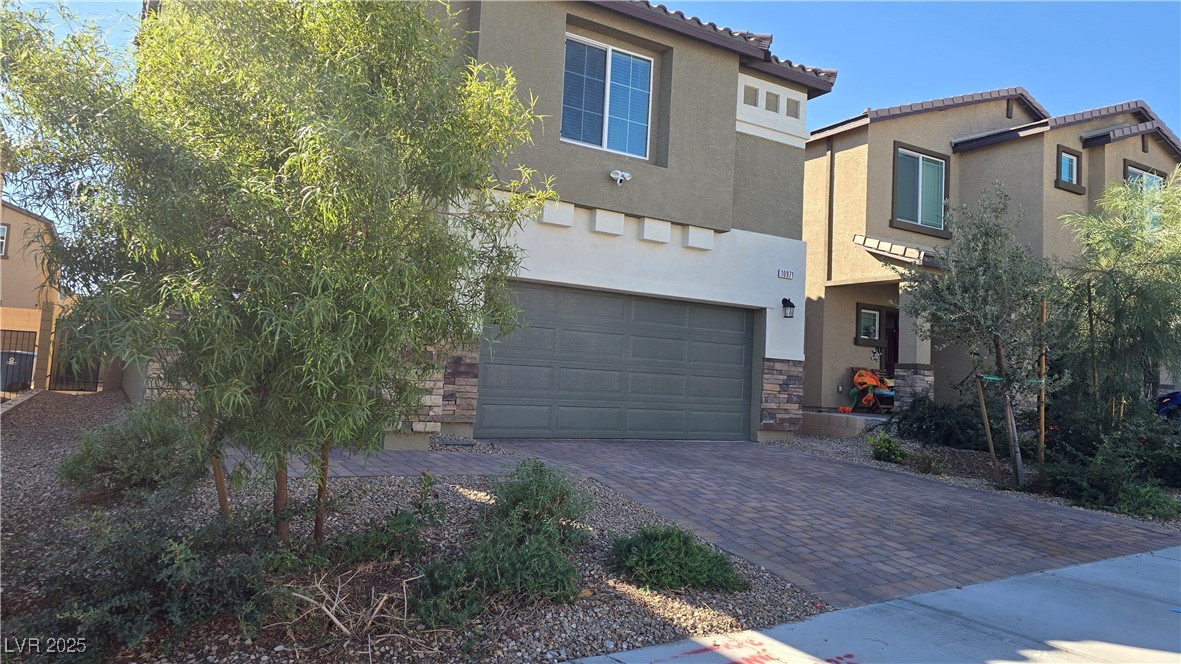 10971 Meridian Fields Avenue Las Vegas, NV 89166 - Photo 2 of 66 View of front of property with stucco siding, decorative driveway, a garage, and stone siding