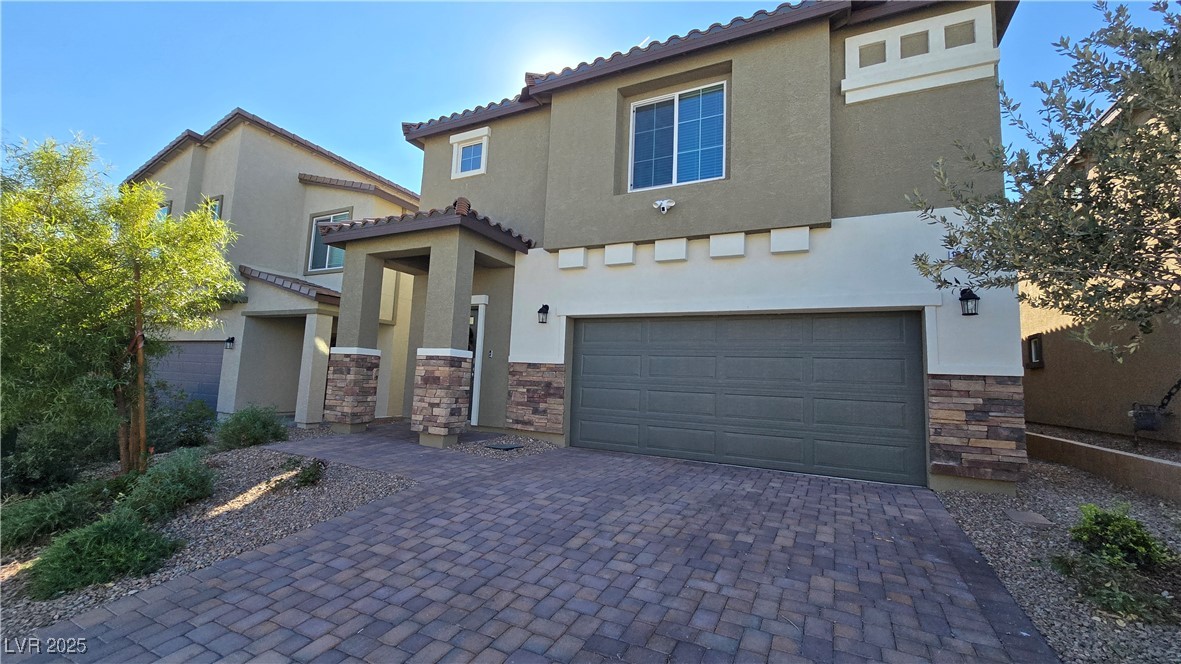10971 Meridian Fields Avenue Las Vegas, NV 89166 - Photo 3 of 66 Mediterranean / spanish home featuring stone siding, stucco siding, an attached garage, decorative driveway, and a tile roof