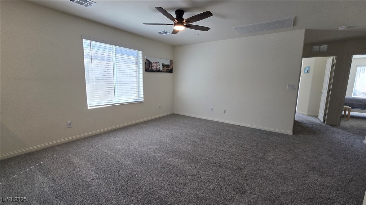 10971 Meridian Fields Avenue Las Vegas, NV 89166 - Photo 39 of 66 Empty room featuring healthy amount of natural light, dark carpet, and ceiling fan