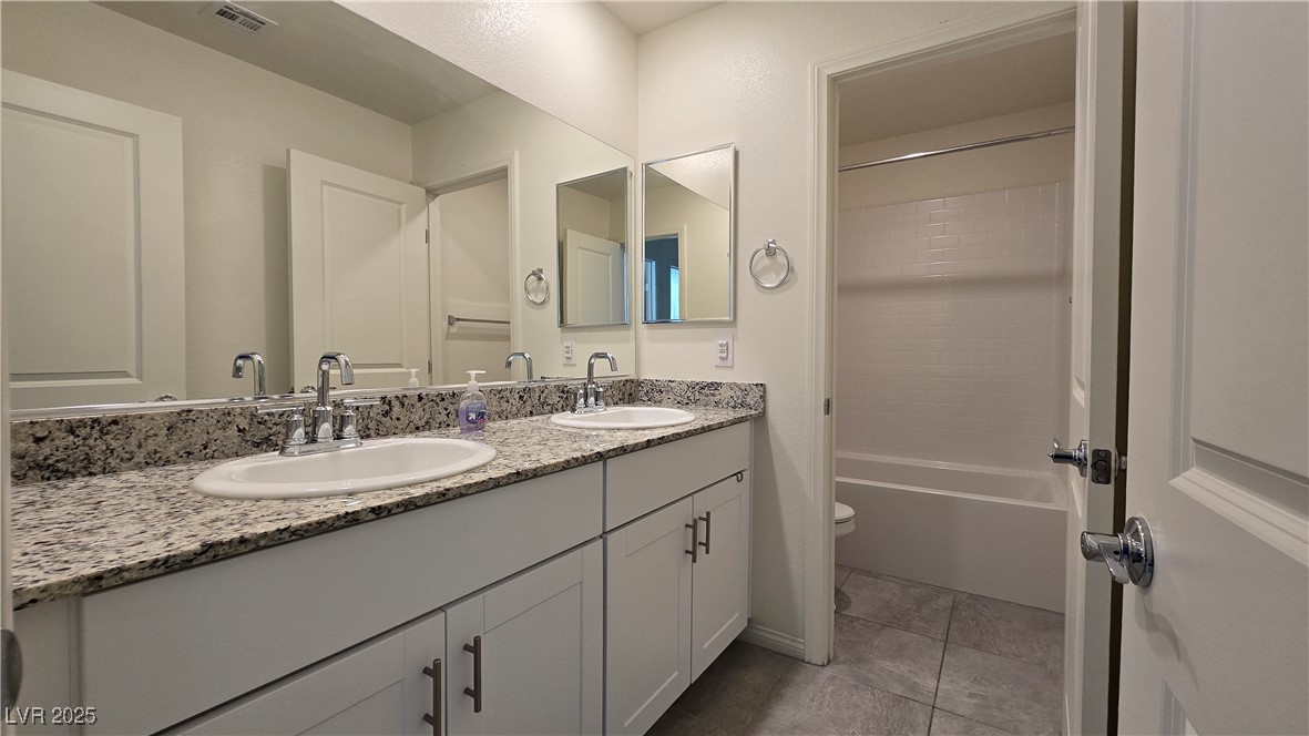 10971 Meridian Fields Avenue Las Vegas, NV 89166 - Photo 45 of 66 Full bath with double vanity, shower / tub combination, and light tile patterned flooring