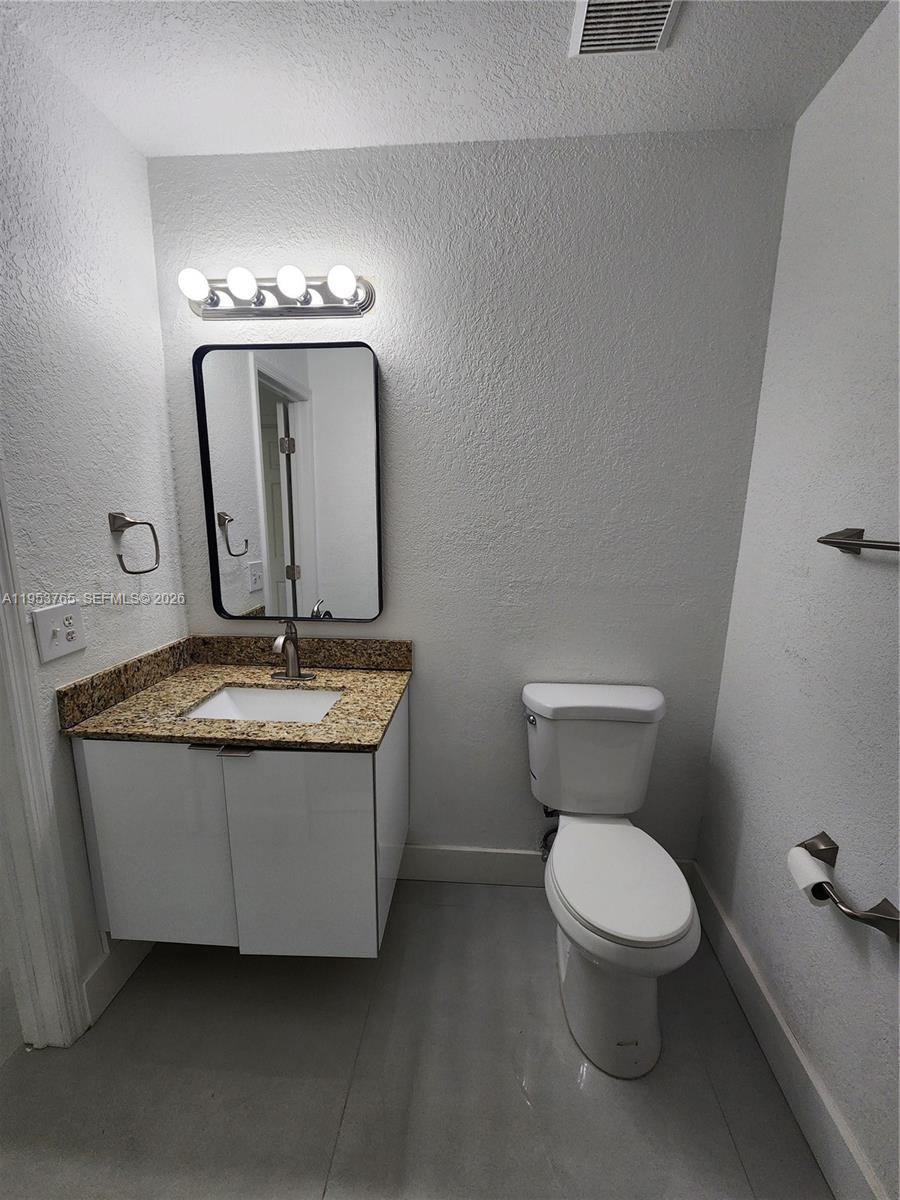 8025 Northwest 8th Street, Unit 10 Miami, FL 33126 - Photo 26 of 26 a bathroom with a granite countertop toilet a sink and a mirror