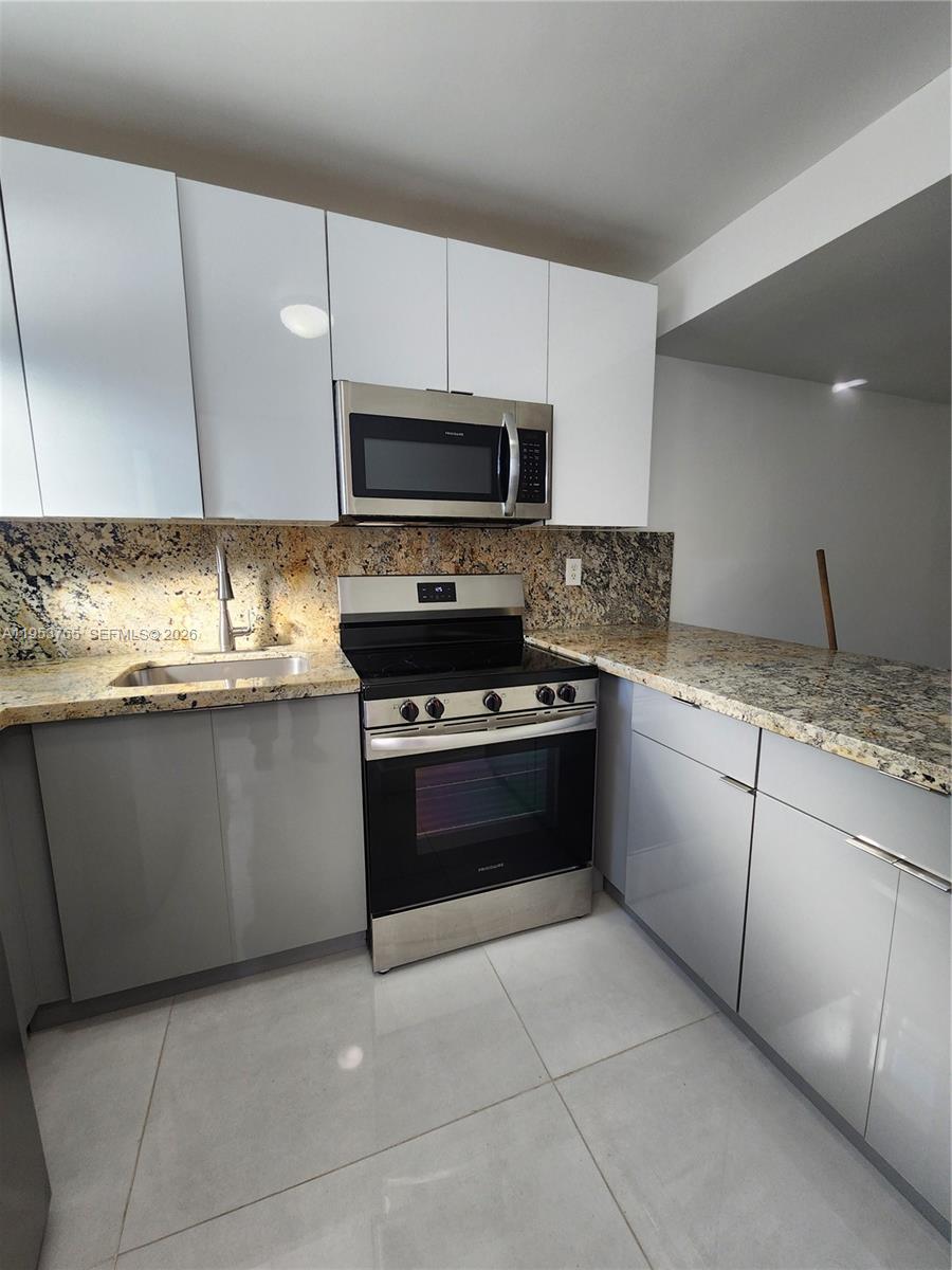 8025 Northwest 8th Street, Unit 10 Miami, FL 33126 - Photo 5 of 26 a kitchen with granite countertop a sink a stove and cabinets