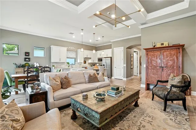 a living room with furniture a rug kitchen view and a chandelier