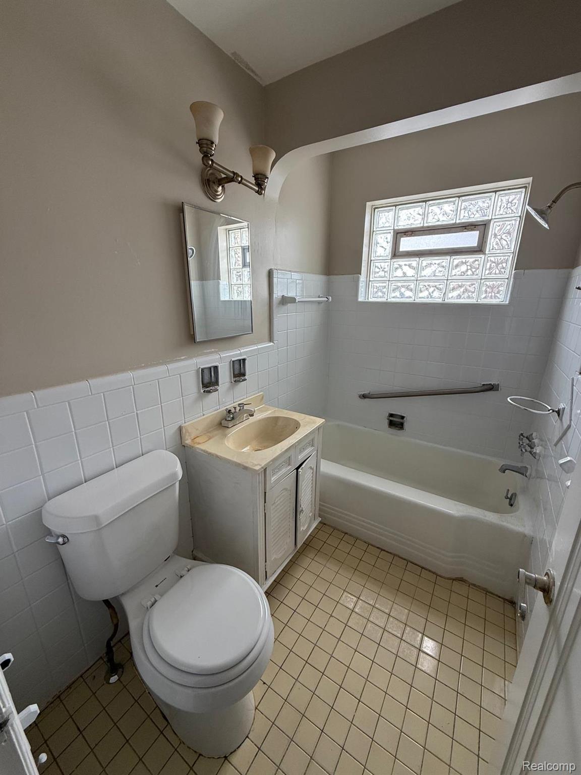 20231 Moross Road Detroit, MI 48224 - Photo 13 of 23 Full bathroom with tile walls, vanity, a wainscoted wall, healthy amount of natural light, and light tile patterned floors