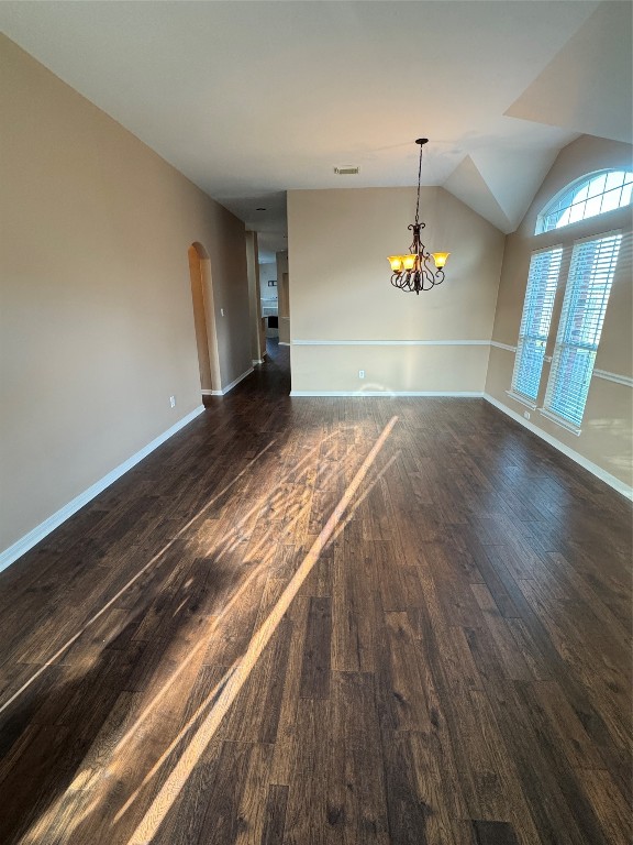 an empty room with wooden floor and chandelier