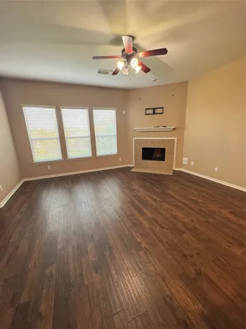 a view of an empty room with wooden floor fireplace and a window