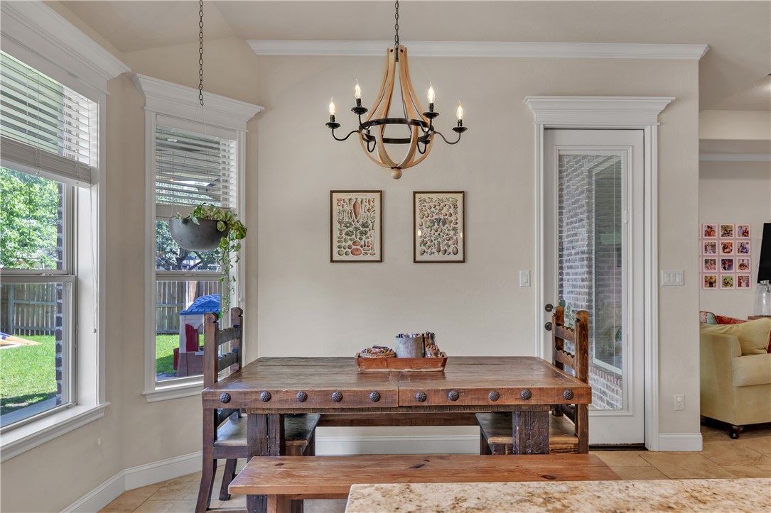 8312 Raintree Drive College Station, TX 77845 - Photo 14 of 30 Dining area featuring a wood-finish chandelier, a bay window with natural light, a full-lite exterior door, and crown molding
