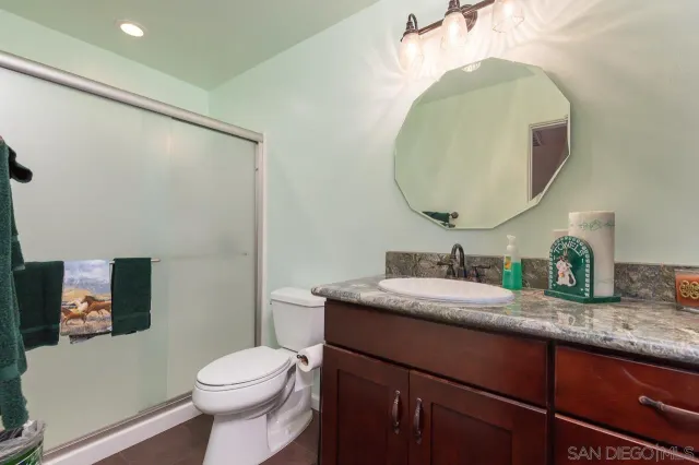 a bathroom with a granite countertop sink mirror vanity and toilet