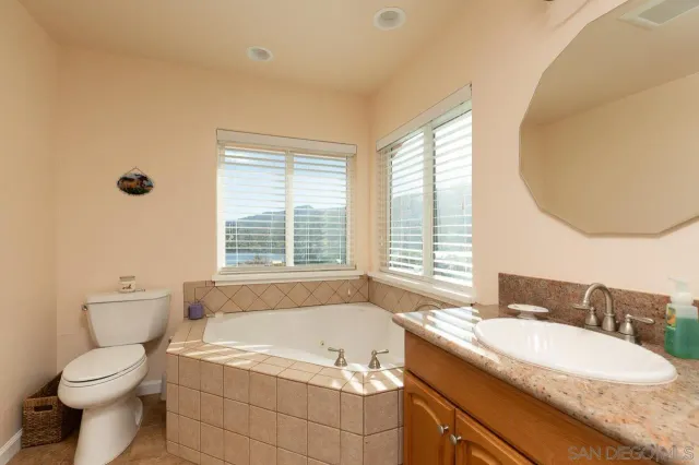 a bathroom with a granite countertop sink and a bathtub