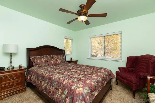 a bedroom with a bed two couch and a window