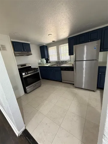 a kitchen with granite countertop a refrigerator and a stove top oven