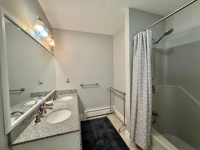 a bathroom with a granite countertop sink a mirror and shower