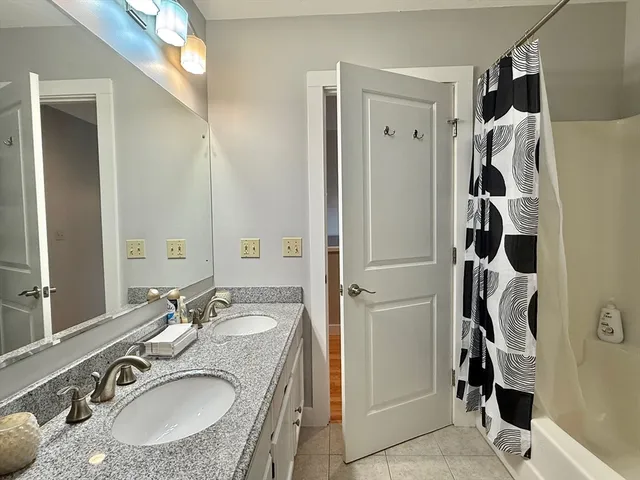 a bathroom with a granite countertop shower sink and mirror