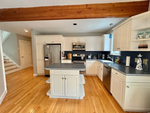 a kitchen with stainless steel appliances granite countertop a stove a sink dishwasher and a refrigerator with wooden floor