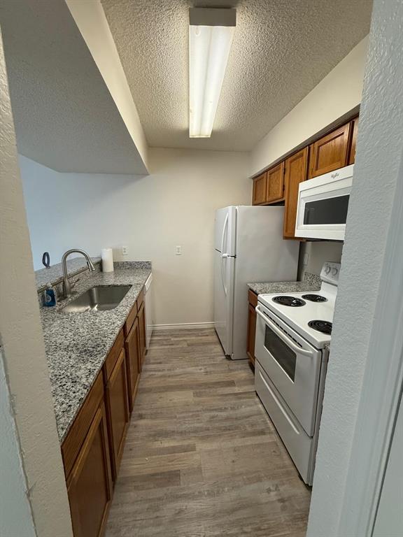 9807 Walnut Street, Unit D 304 Dallas, TX 75243 - Photo 1 of 7 a kitchen with granite countertop a sink and a refrigerator