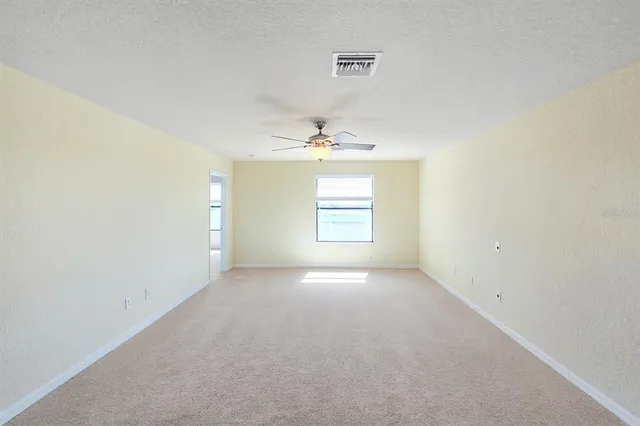 an empty room with windows and a ceiling fan