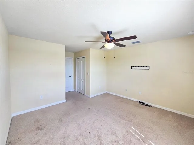an empty room with windows and fan