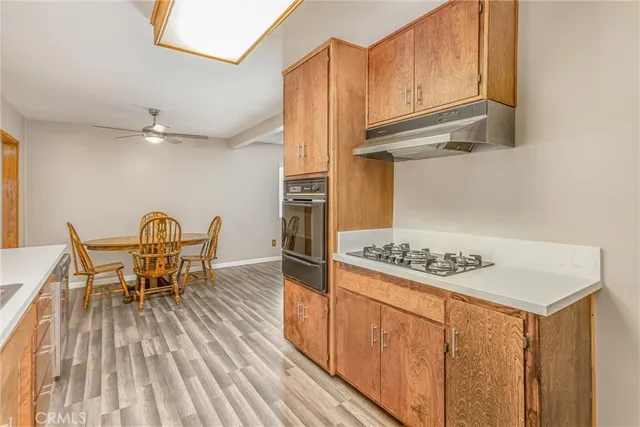 a kitchen with stainless steel appliances granite countertop a stove top oven a dining table and chairs with wooden floor