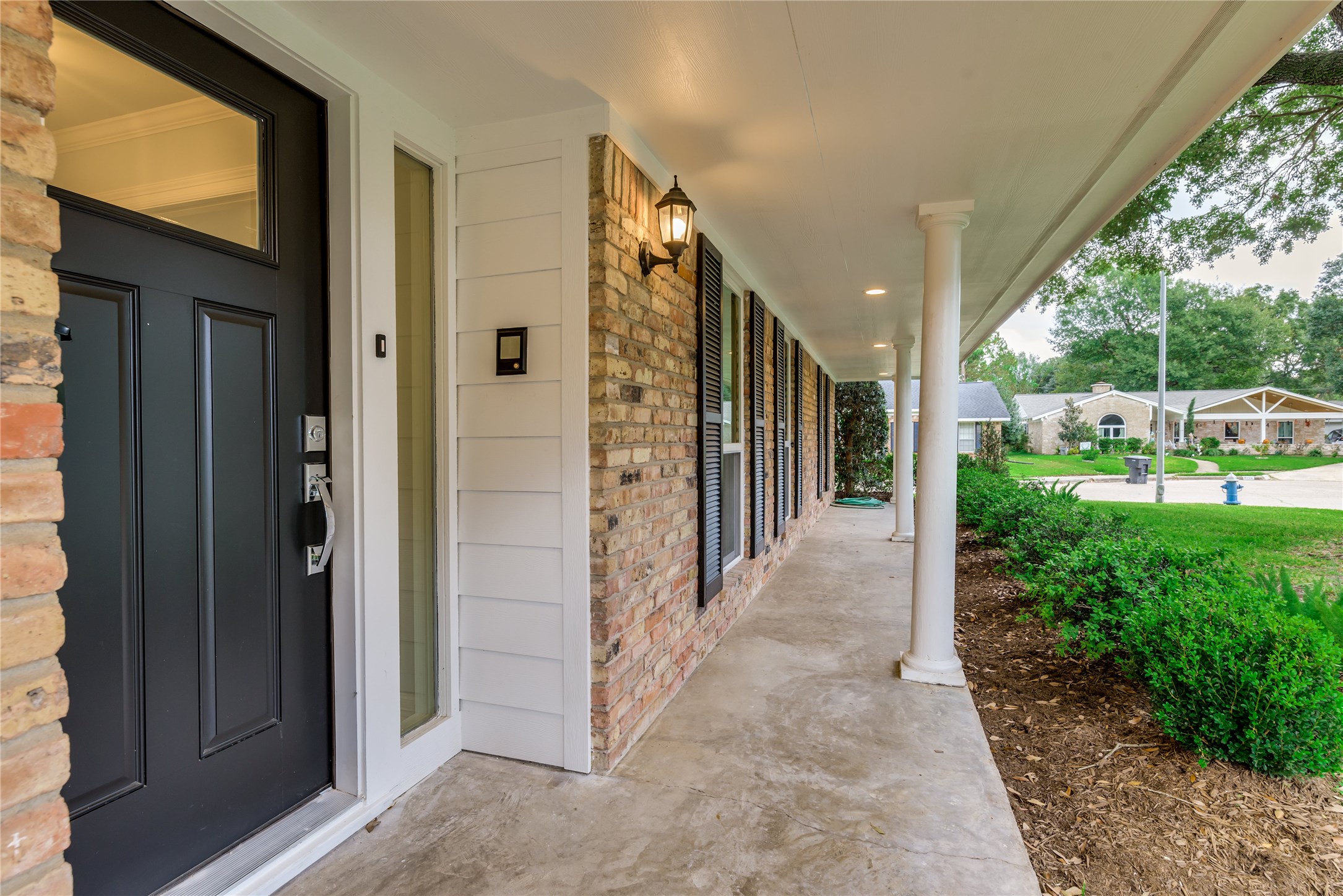 1010 Thornton Road Houston, TX 77018 - Photo 2 of 27 Charming front porch with elegant columns and a brick facade, complemented by a modern black door. The wide pathway and well-maintained landscaping offer a welcoming entrance.